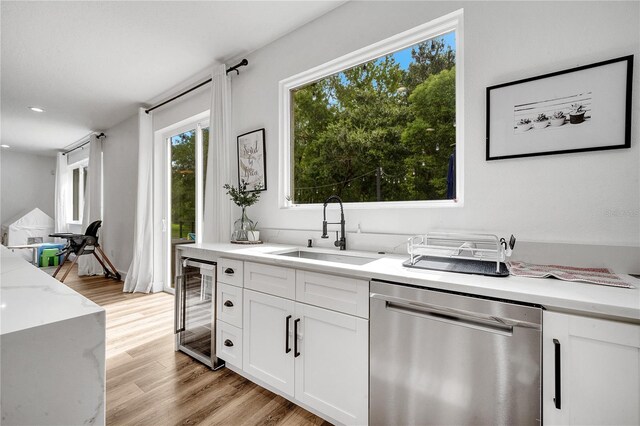 kitchen featuring dishwasher, light hardwood / wood-style flooring, white cabinetry, sink, and wine cooler