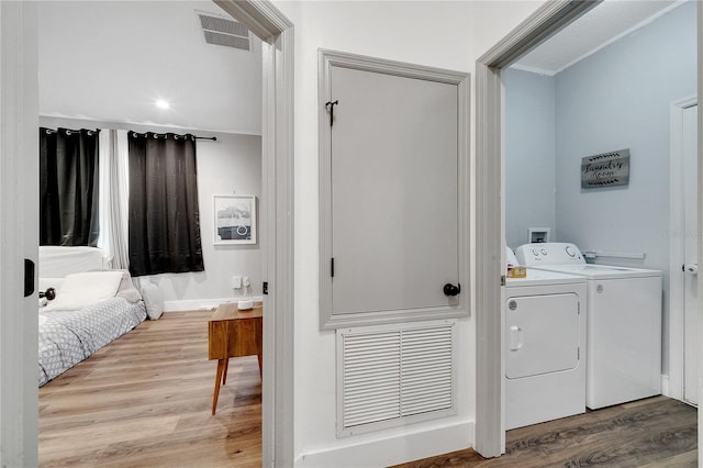 clothes washing area with washer and clothes dryer and light hardwood / wood-style floors