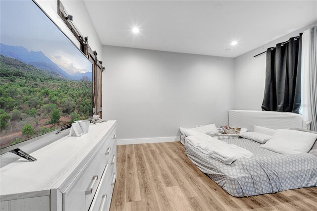 bedroom featuring a barn door and light wood-type flooring