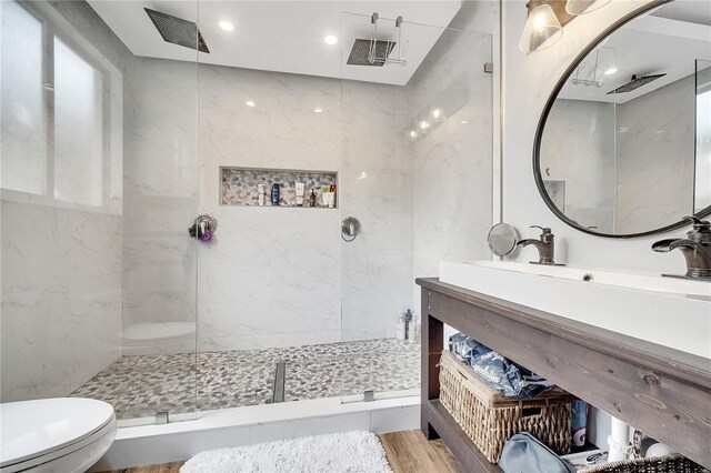 bathroom with vanity, toilet, wood-type flooring, and a tile shower