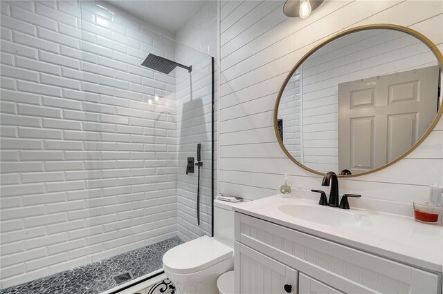 bathroom featuring vanity, toilet, a tile shower, and wooden walls