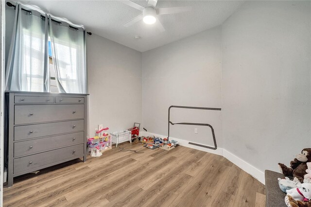 playroom with a textured ceiling, light hardwood / wood-style flooring, and ceiling fan