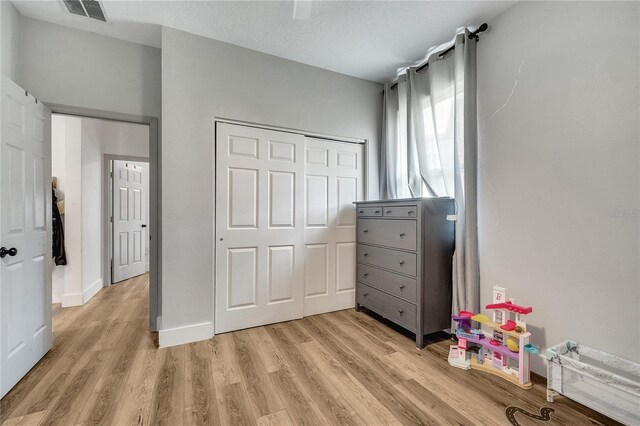 bedroom featuring light hardwood / wood-style floors, a textured ceiling, and a closet