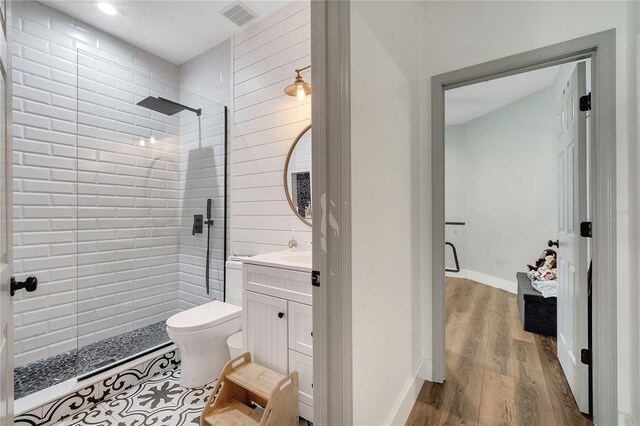 bathroom with tiled shower, vanity, toilet, and hardwood / wood-style floors