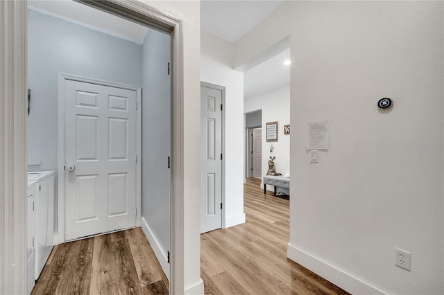 hallway with washing machine and dryer and light hardwood / wood-style floors