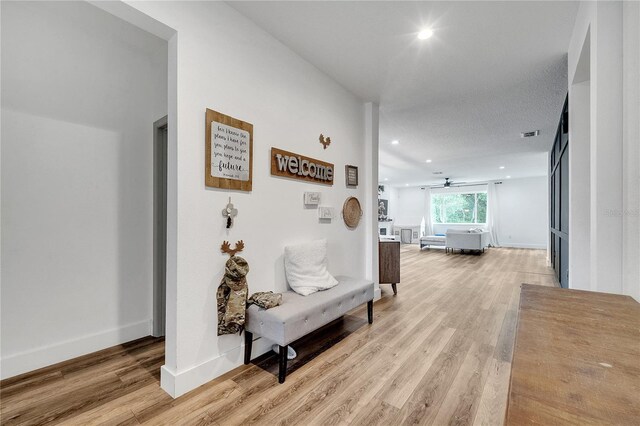 corridor featuring a textured ceiling and light hardwood / wood-style floors