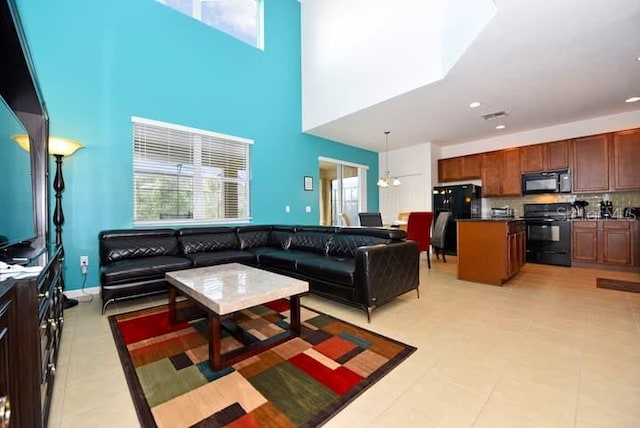 living room featuring ceiling fan, a towering ceiling, and light tile patterned floors