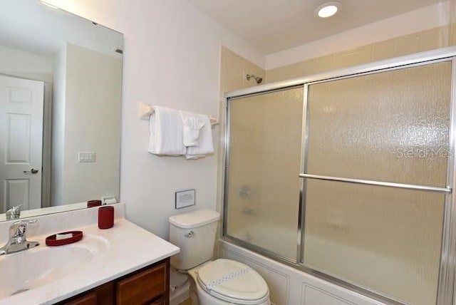 full bathroom featuring combined bath / shower with glass door, vanity, and toilet