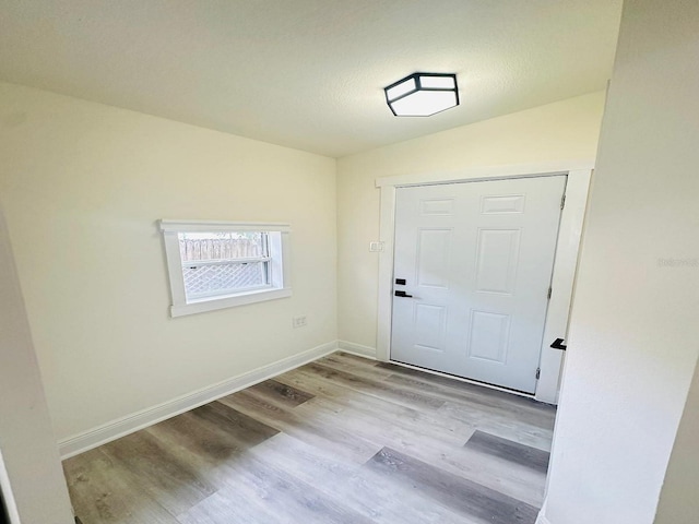 doorway with light wood-type flooring and lofted ceiling