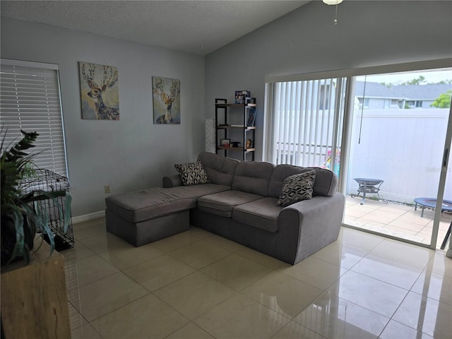 living room featuring vaulted ceiling, a textured ceiling, and light tile patterned floors