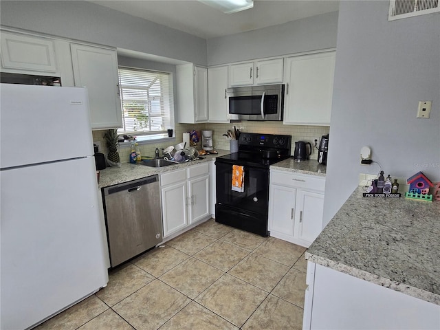 kitchen featuring white cabinets, appliances with stainless steel finishes, light tile patterned floors, and decorative backsplash