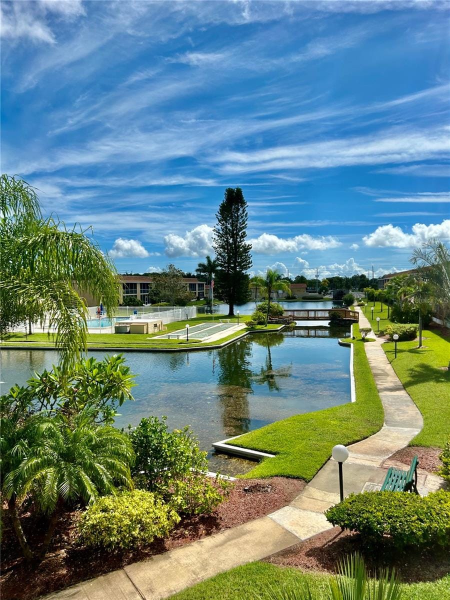 view of property's community featuring a lawn and a water view