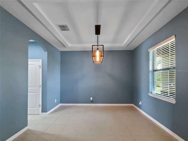 spare room with arched walkways, baseboards, visible vents, and a tray ceiling