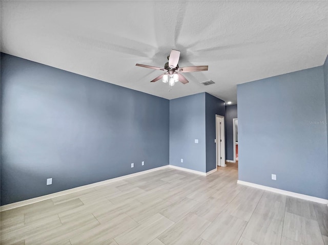 unfurnished room featuring a ceiling fan, visible vents, a textured ceiling, and baseboards