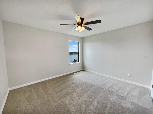 carpeted empty room featuring ceiling fan, a textured ceiling, and baseboards