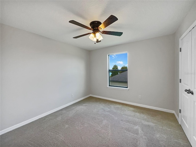 carpeted spare room featuring a ceiling fan and baseboards