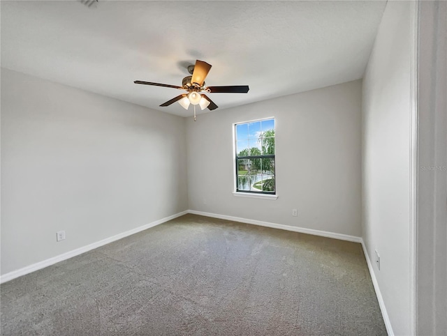 carpeted spare room featuring a ceiling fan and baseboards