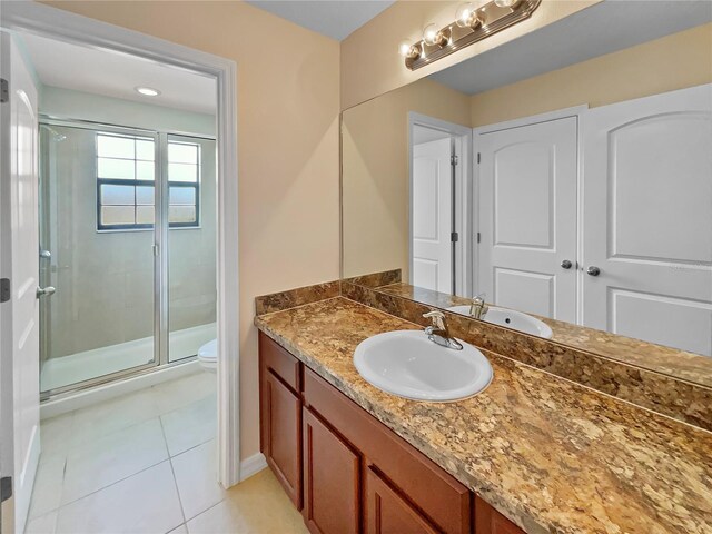 bathroom with baseboards, toilet, tile patterned floors, vanity, and a shower stall