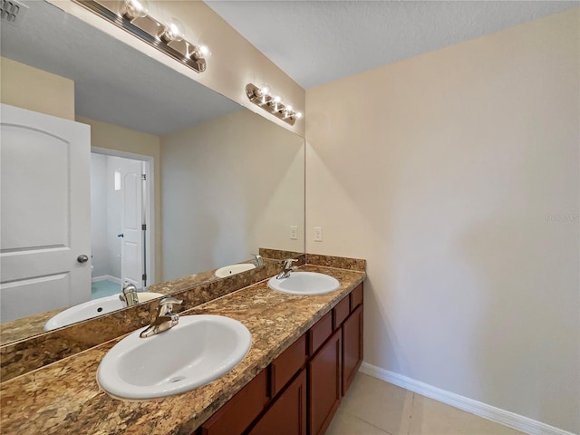 bathroom with double vanity, a sink, and baseboards