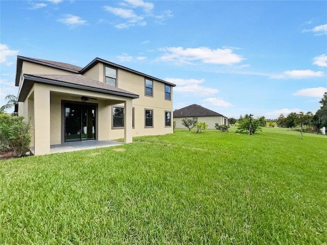 rear view of house with a yard, a ceiling fan, a patio, and stucco siding