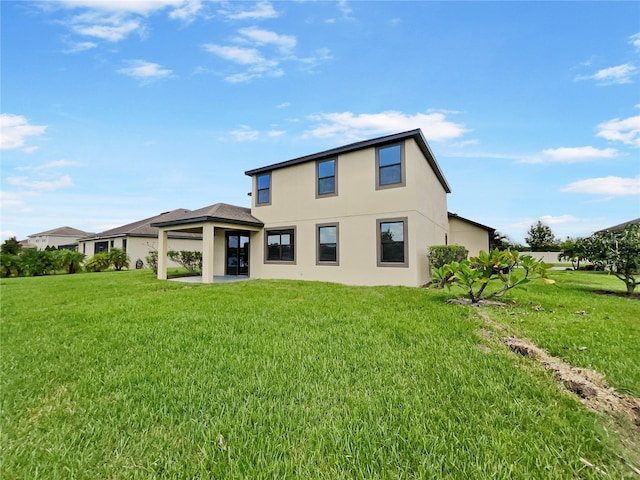 rear view of property featuring a yard and stucco siding