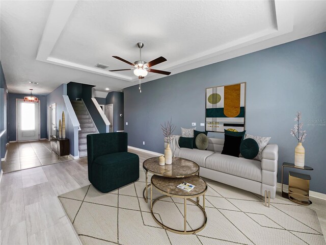 living room featuring a tray ceiling and ceiling fan