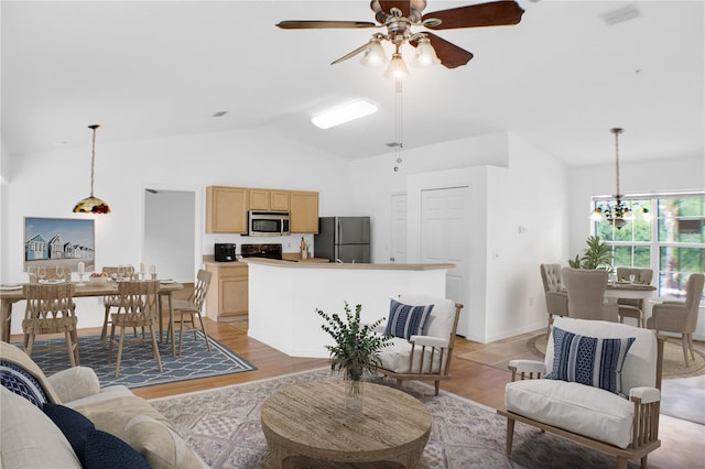 living room with vaulted ceiling, light hardwood / wood-style flooring, and ceiling fan with notable chandelier