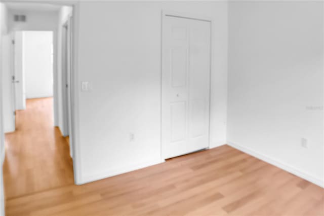 unfurnished bedroom featuring a closet, baseboards, visible vents, and light wood finished floors