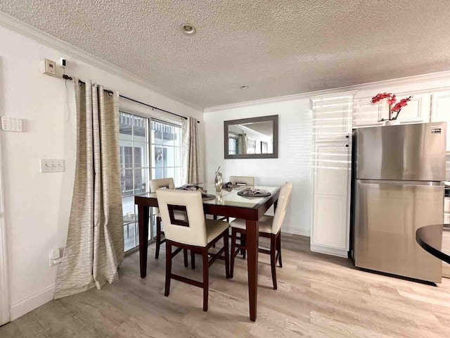 dining room featuring ornamental molding, a textured ceiling, and light wood-type flooring