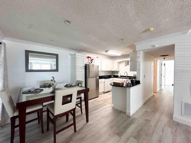 kitchen featuring stainless steel fridge, light hardwood / wood-style flooring, white dishwasher, ornamental molding, and white cabinets