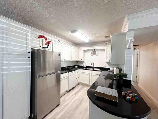 kitchen featuring sink, light wood-type flooring, stainless steel fridge, dishwasher, and white cabinets