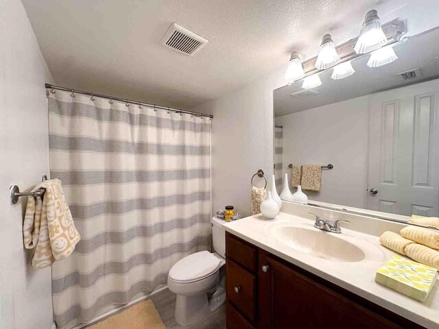 bathroom with vanity, toilet, and a textured ceiling