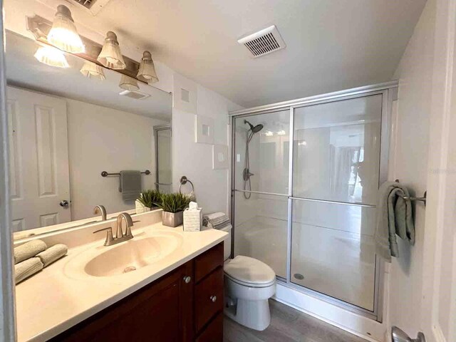 bathroom featuring walk in shower, vanity, and toilet