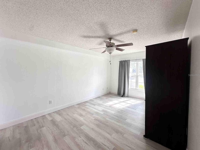 unfurnished room featuring ceiling fan, a textured ceiling, and light wood-type flooring