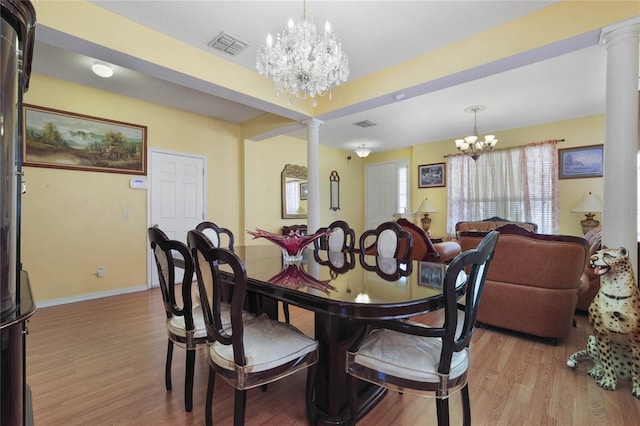 dining area featuring light hardwood / wood-style floors, decorative columns, and an inviting chandelier