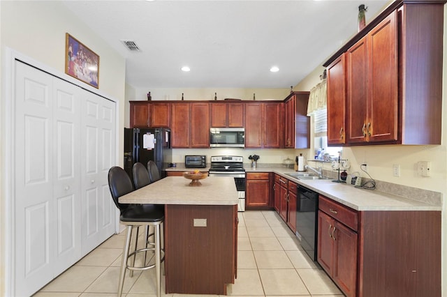 kitchen featuring black appliances, a kitchen island, a kitchen bar, and light tile patterned floors