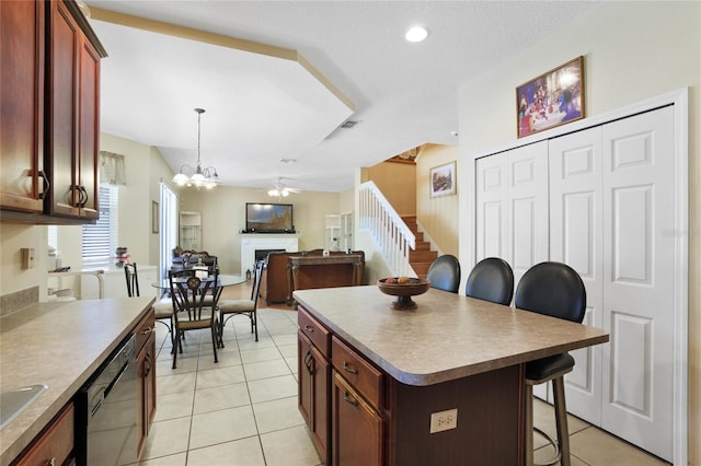 kitchen with a kitchen breakfast bar, ceiling fan with notable chandelier, a center island, hanging light fixtures, and light tile patterned flooring