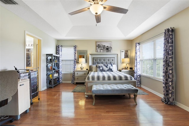 bedroom featuring hardwood / wood-style floors, ceiling fan, a raised ceiling, and a textured ceiling