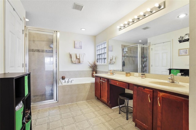 bathroom with vanity, a textured ceiling, and separate shower and tub