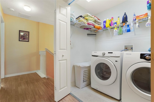 clothes washing area featuring washing machine and clothes dryer and light hardwood / wood-style floors