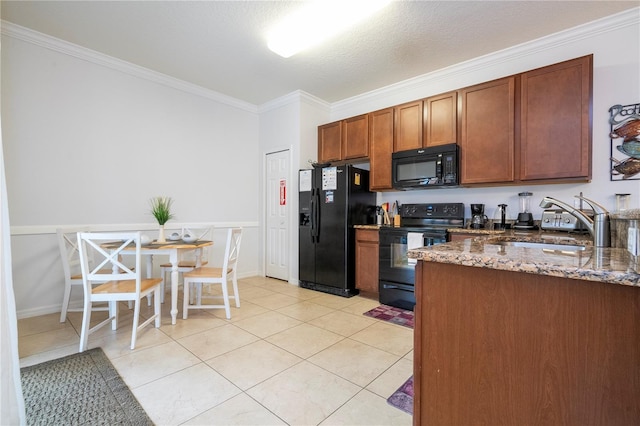 kitchen with sink, light tile patterned flooring, black appliances, and dark stone counters