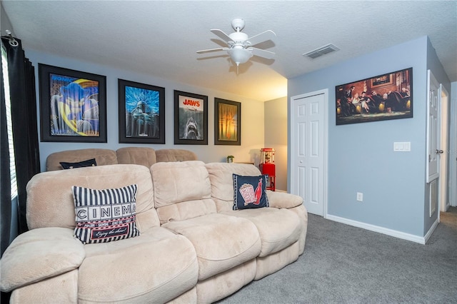 living room featuring ceiling fan, carpet flooring, and a textured ceiling