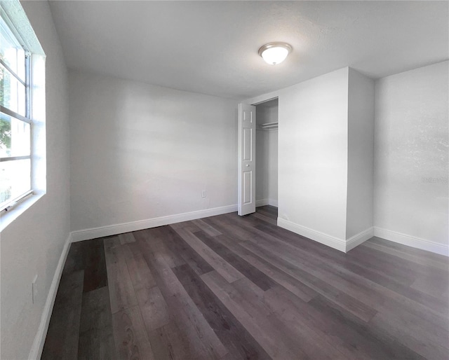 unfurnished bedroom featuring dark hardwood / wood-style flooring and a closet