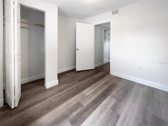 unfurnished bedroom with dark hardwood / wood-style flooring and a closet