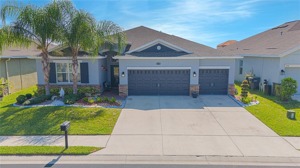 craftsman-style house with a garage, concrete driveway, a front lawn, and stucco siding