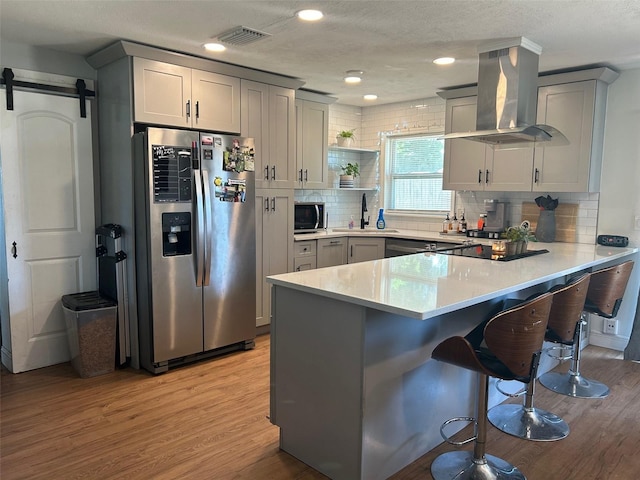 kitchen with stainless steel appliances, a barn door, a sink, a peninsula, and extractor fan