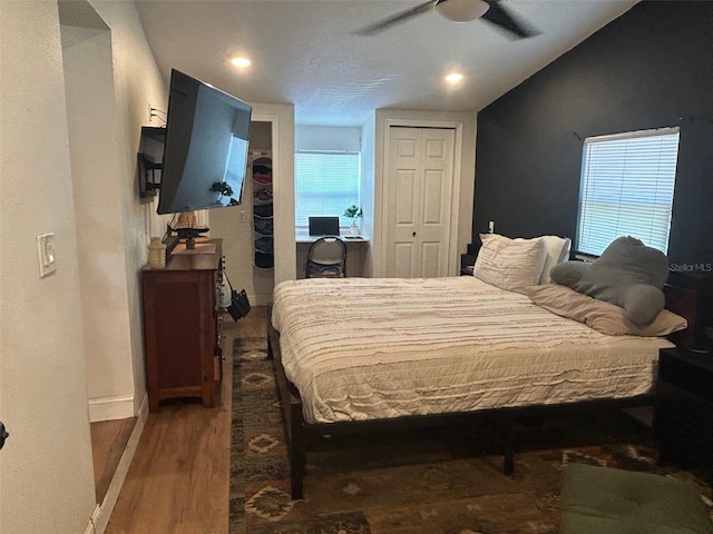 bedroom with multiple windows, baseboards, vaulted ceiling, and wood finished floors