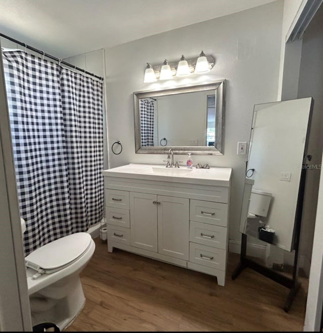 bathroom featuring toilet, a shower with shower curtain, wood finished floors, and vanity