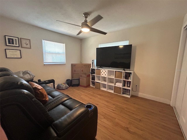 living area with a ceiling fan, baseboards, and wood finished floors