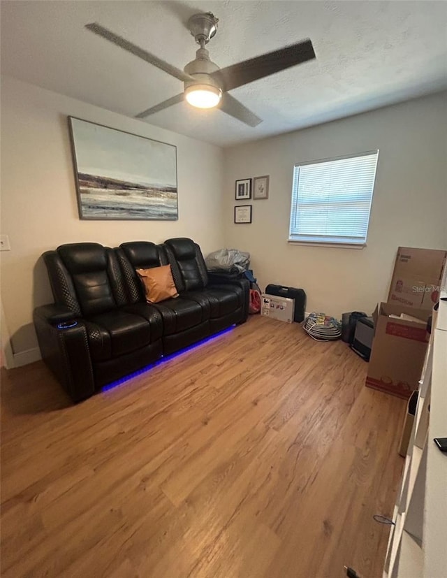 living area with a textured ceiling, a ceiling fan, and wood finished floors